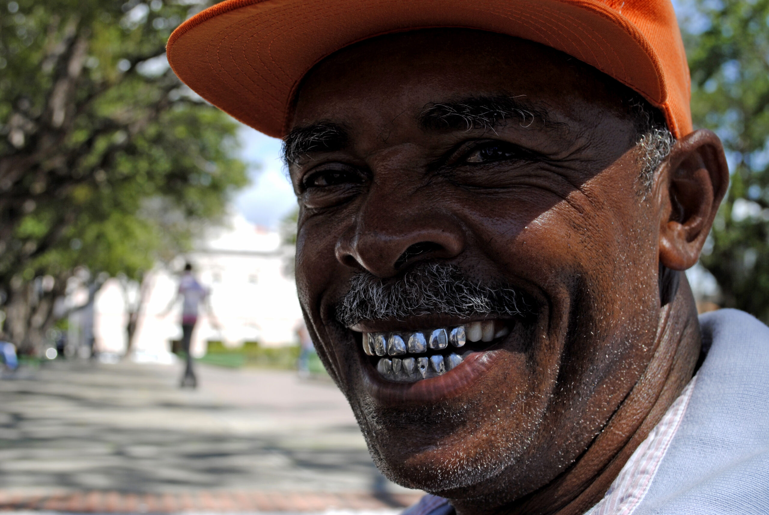 Homem de boné laranja sorrindo, esbanjando felicidade brasileira