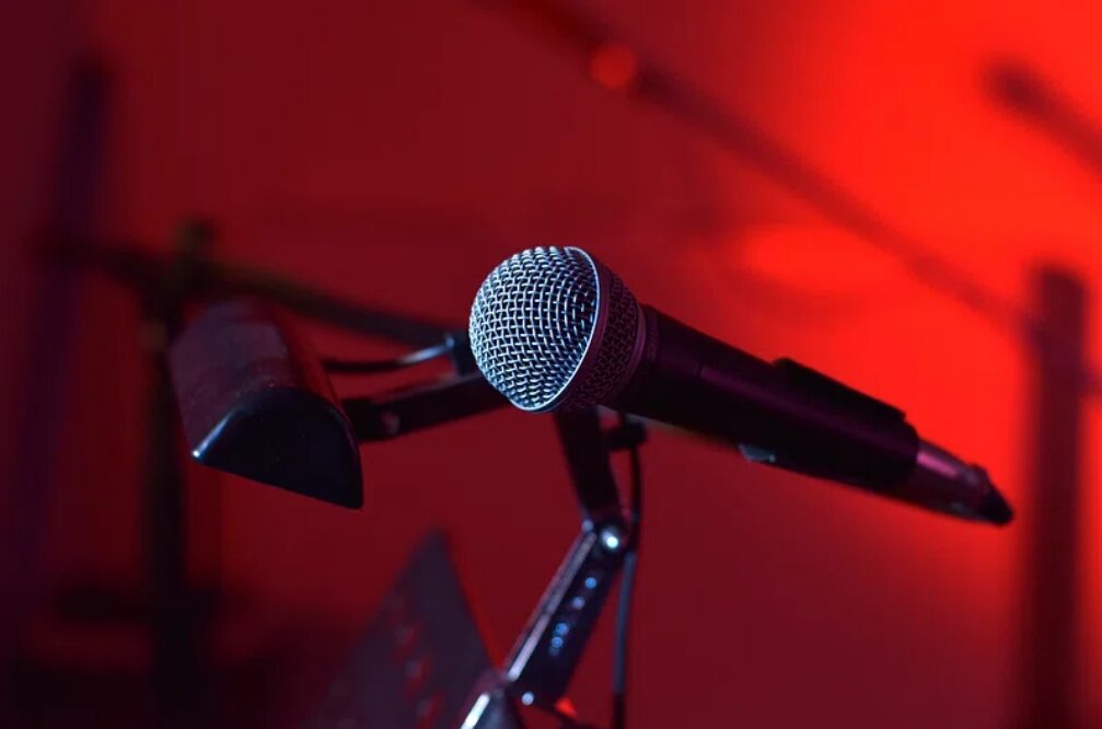 Fotografia de um microfone em um fundo vermelho, objeto utilizado por Leo Lins