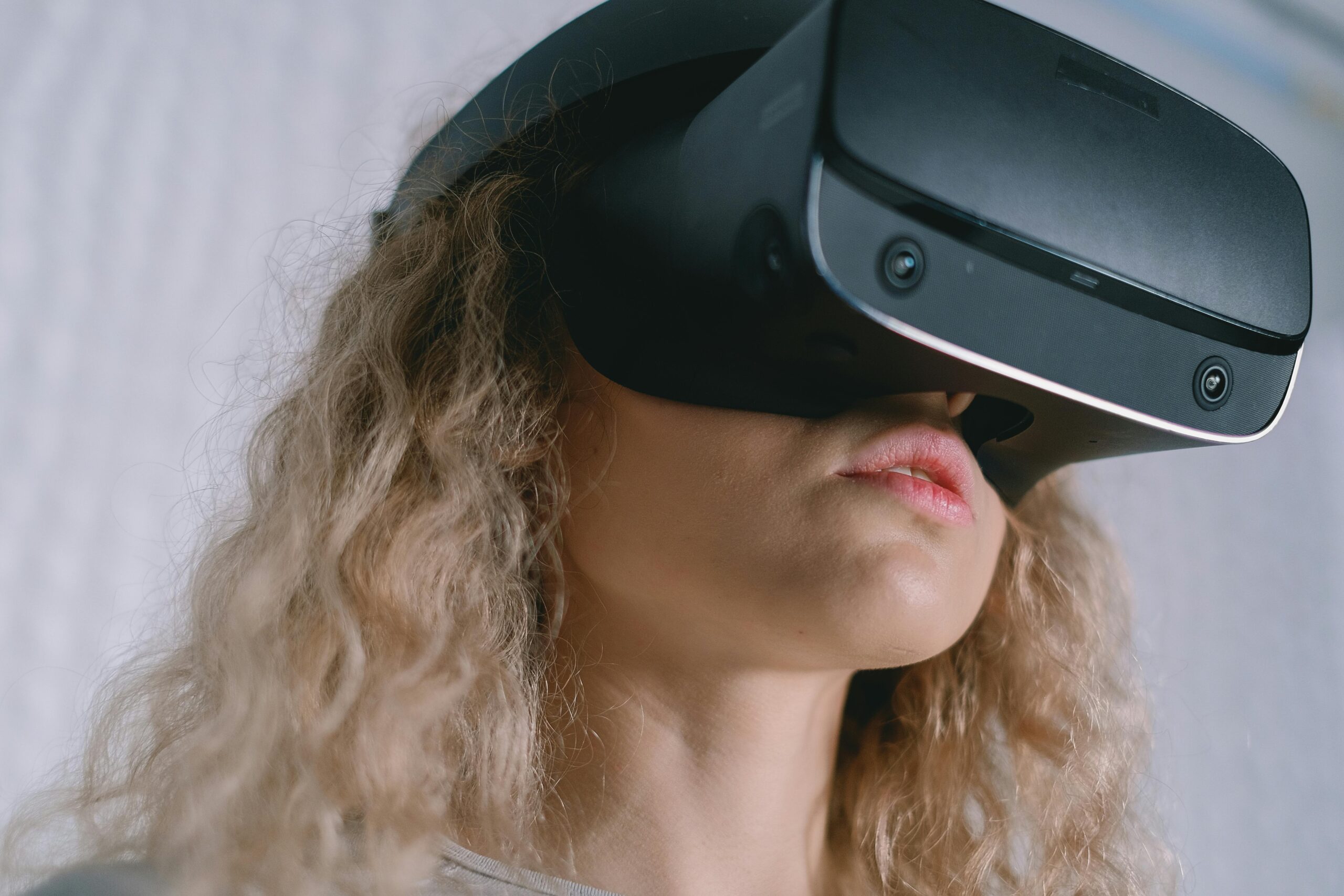 Mundo de IA: Uma menina usa um aparelho de simulação de realidade virtual. Ela tem cabelo loiro.