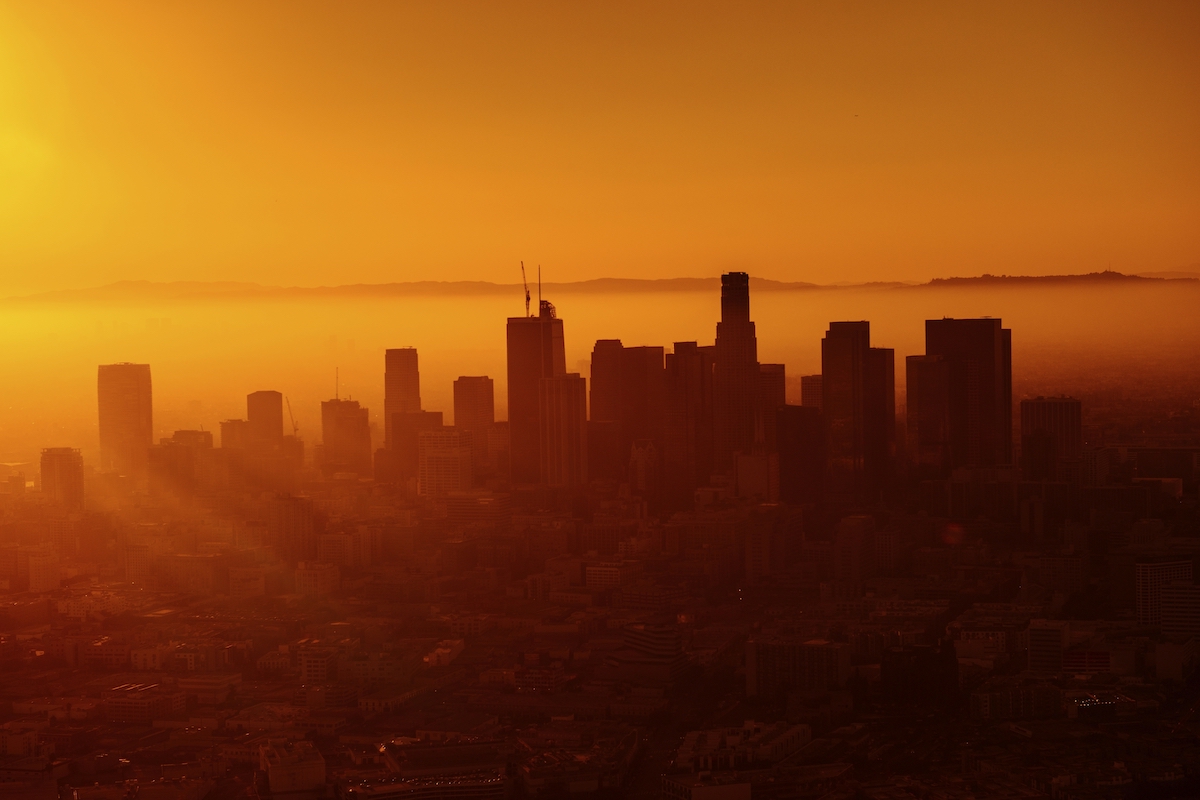 Imagem representando alta temperatura: um panorama de vários prédios sob uma luz laranja do sol
