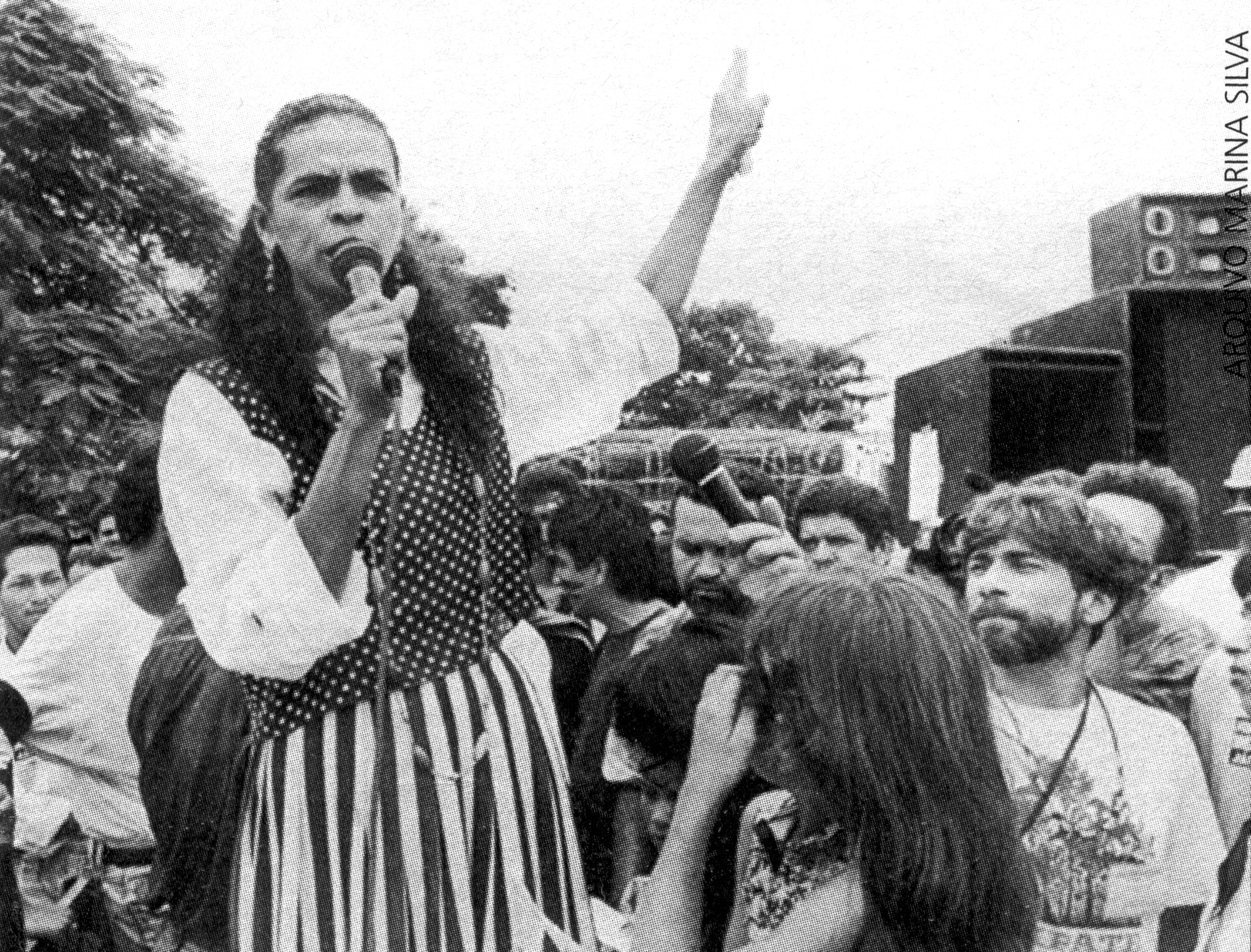 Imagem de Marina Silva, combatendo injustiças em uma manifestação no Acre (1994). Ela segura um microfone.