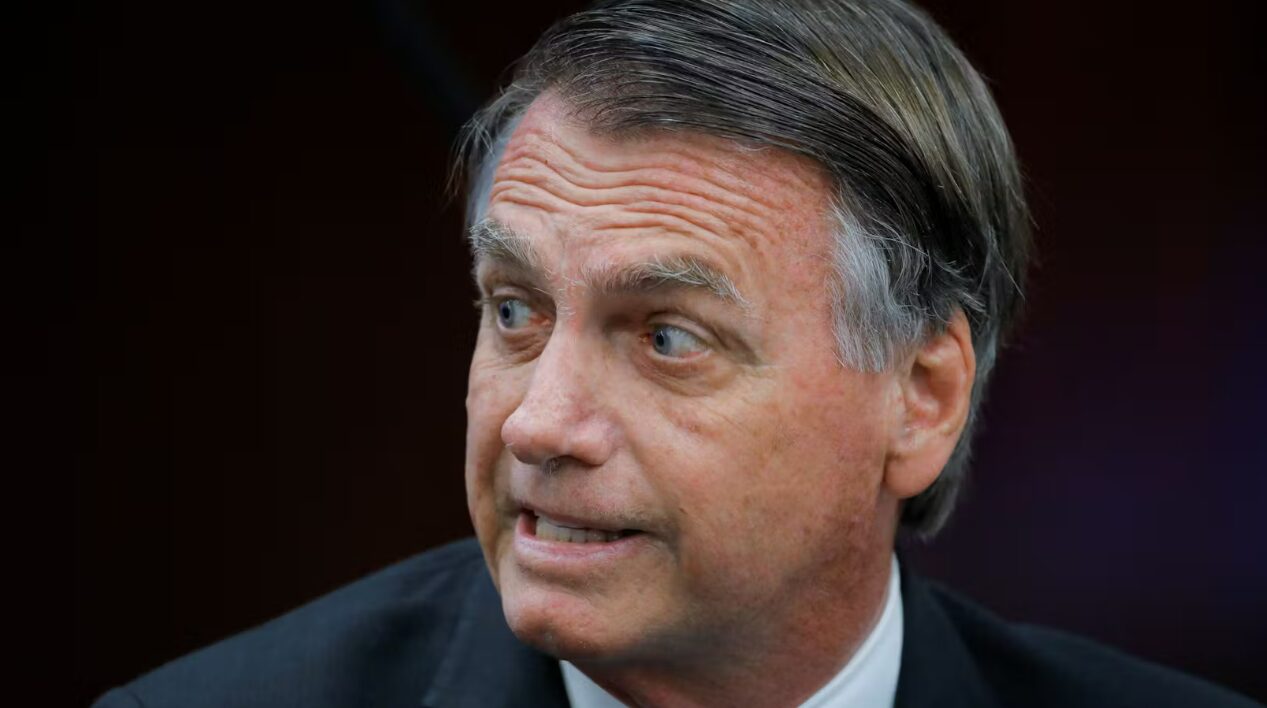 O Bolsonaro olha para o lado com um semblante de indignação. A foto é do pescoço acima.