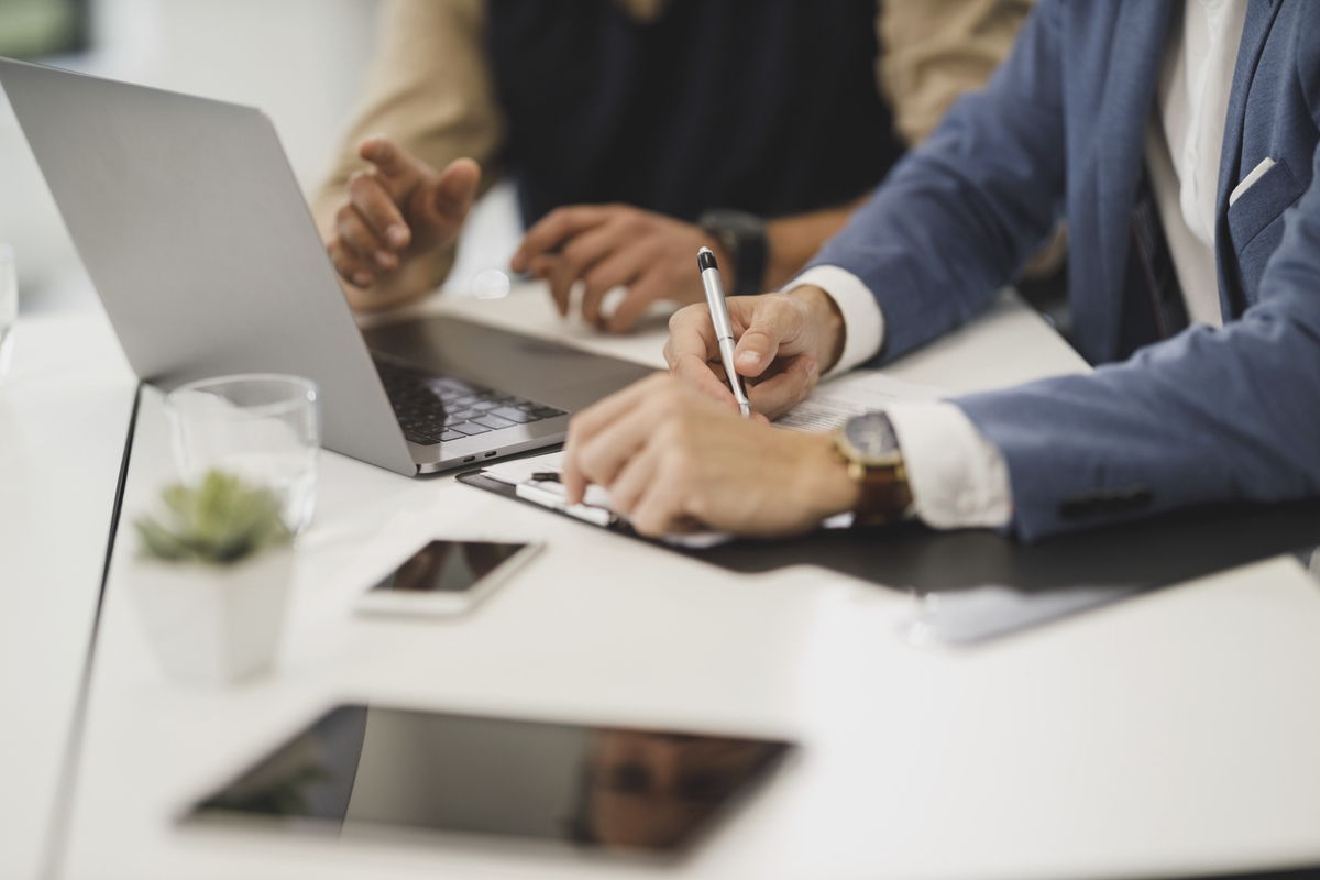 Em um espaço aparentemente empresarial, duas pessoas conversam na frente de um computador.