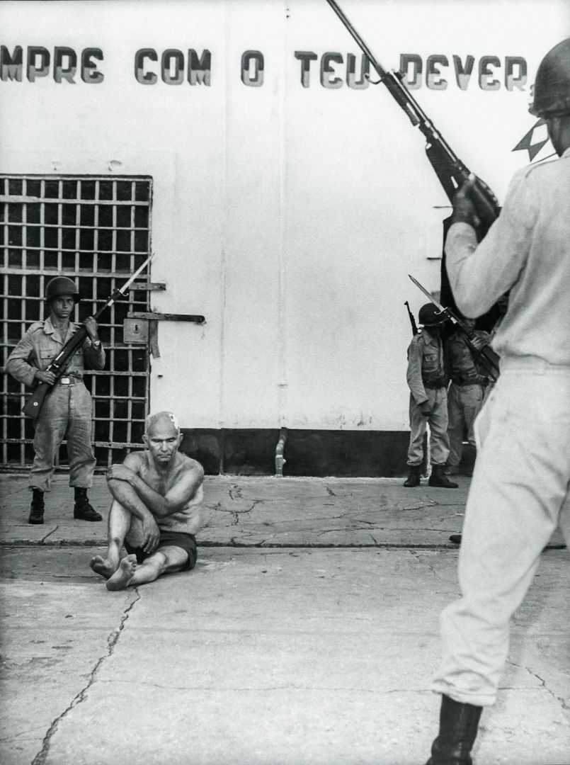 Fotografia de Gregorio Bezerra, do PCB, cercado por quatro militares, em preto e branco. Ele está sem camisa e descalço.