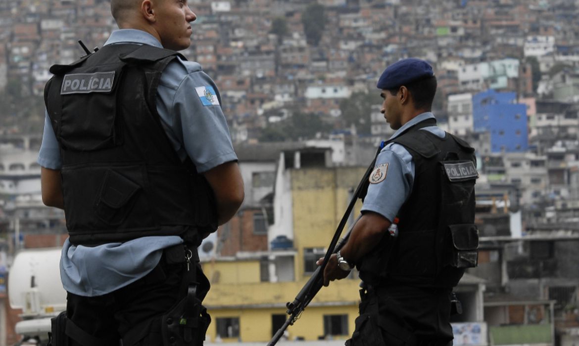 Fotografia de dois policiais na Operação no Rio de Janeiro. Eles estão de costas para a câmera.