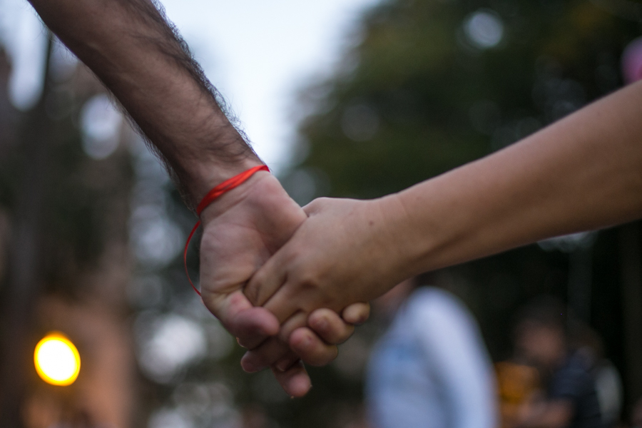 Saúde mental: imagem de duas pessoas dando as mãos. O fundo está desfocado.