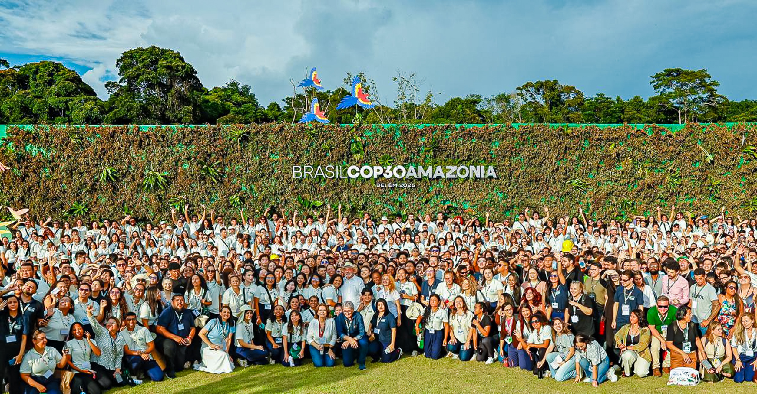 Um olhar crítico sobre a COP 30 e a retórica da transição energética. A fotografia mostra várias pessoas na frente de uma logo escrito "BRASIL COP30 AMAZÔNIA"