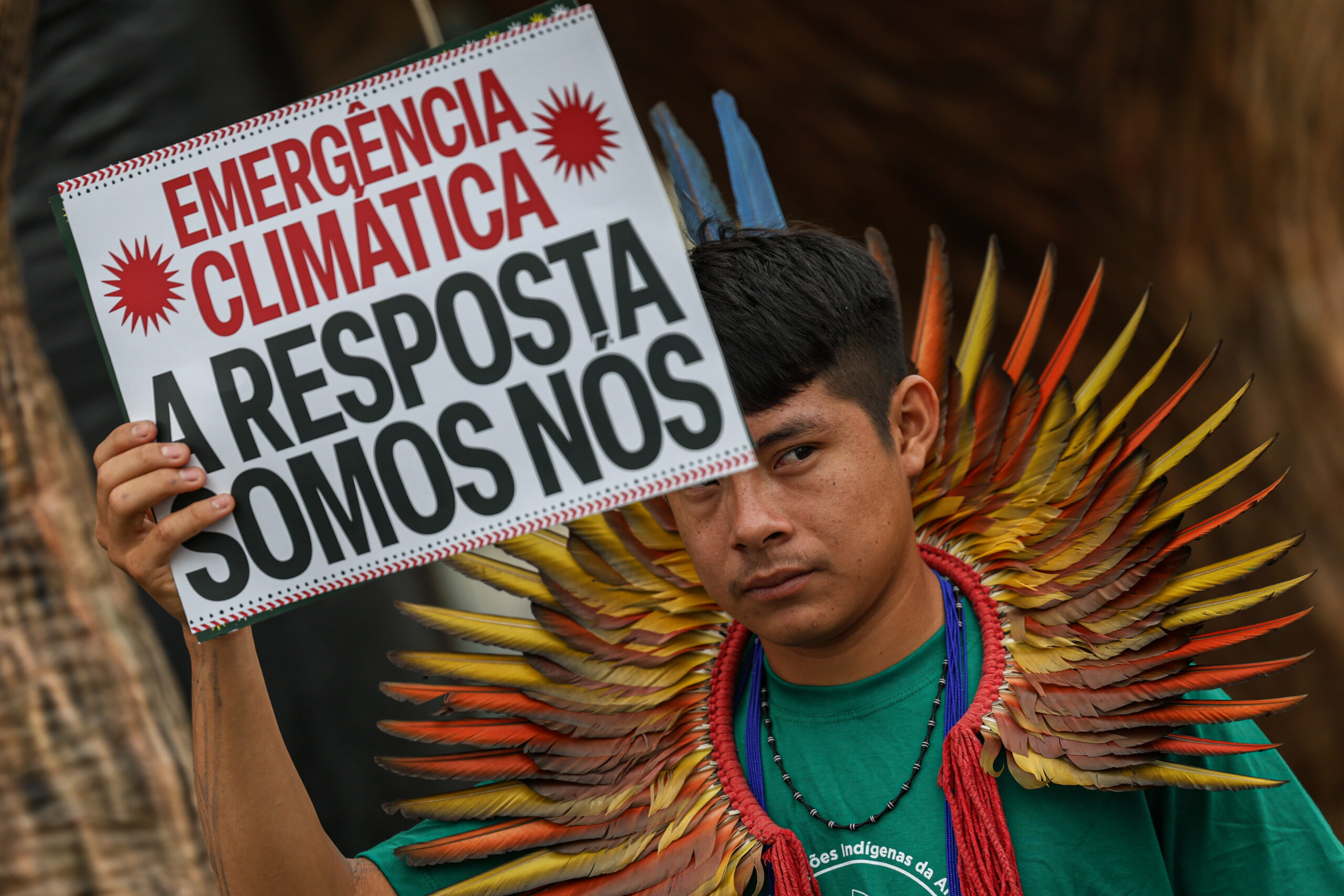 Protestos na COP 30: Homem indígena segura um cartaz em que está escrito "A resposta somos nós"