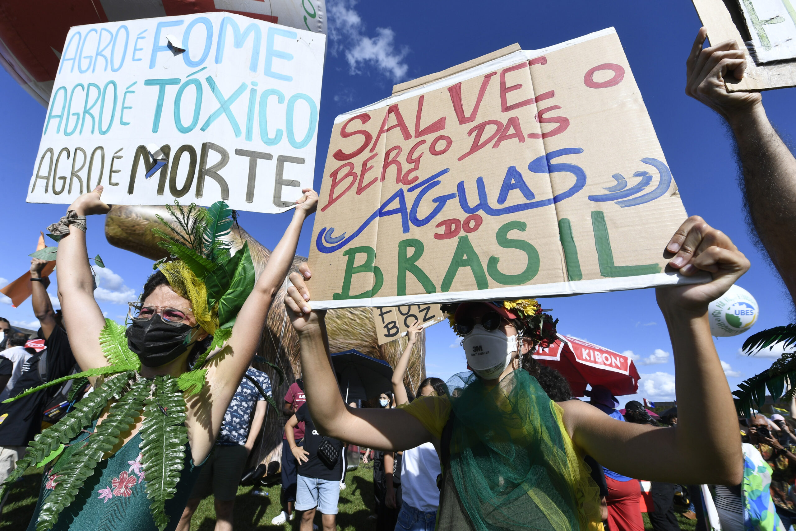 Ativistas se manifestam a favor dos direitos humanos e contra a crise climática. Eles seguram cartazes.