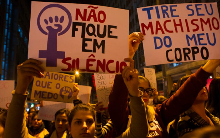 Mulheres protestam contra a violência de gênero. Em uma das placas está escrito "Não fique em silêncio"