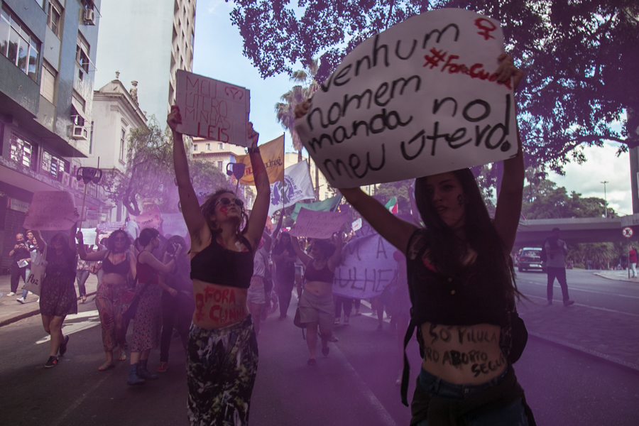 Lutas feministas: colagem de mulheres segurando cartazes em manifestações. Há um filtro lilás na imagem