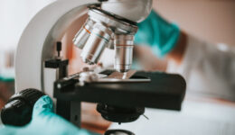 Close-up of a lab technitian applying a sample to a microscope g